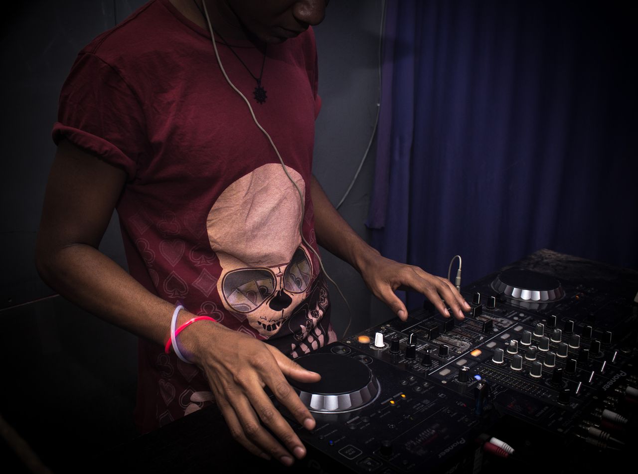 Man DJing with turntables indoors, creating vibrant party atmosphere.