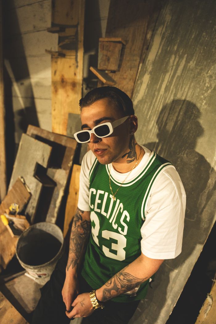 Creative portrait of a stylish man with tattoos wearing a Celtics jersey indoors.