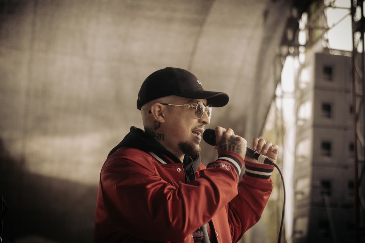A rapper passionately performing on an outdoor stage, capturing live music energy.