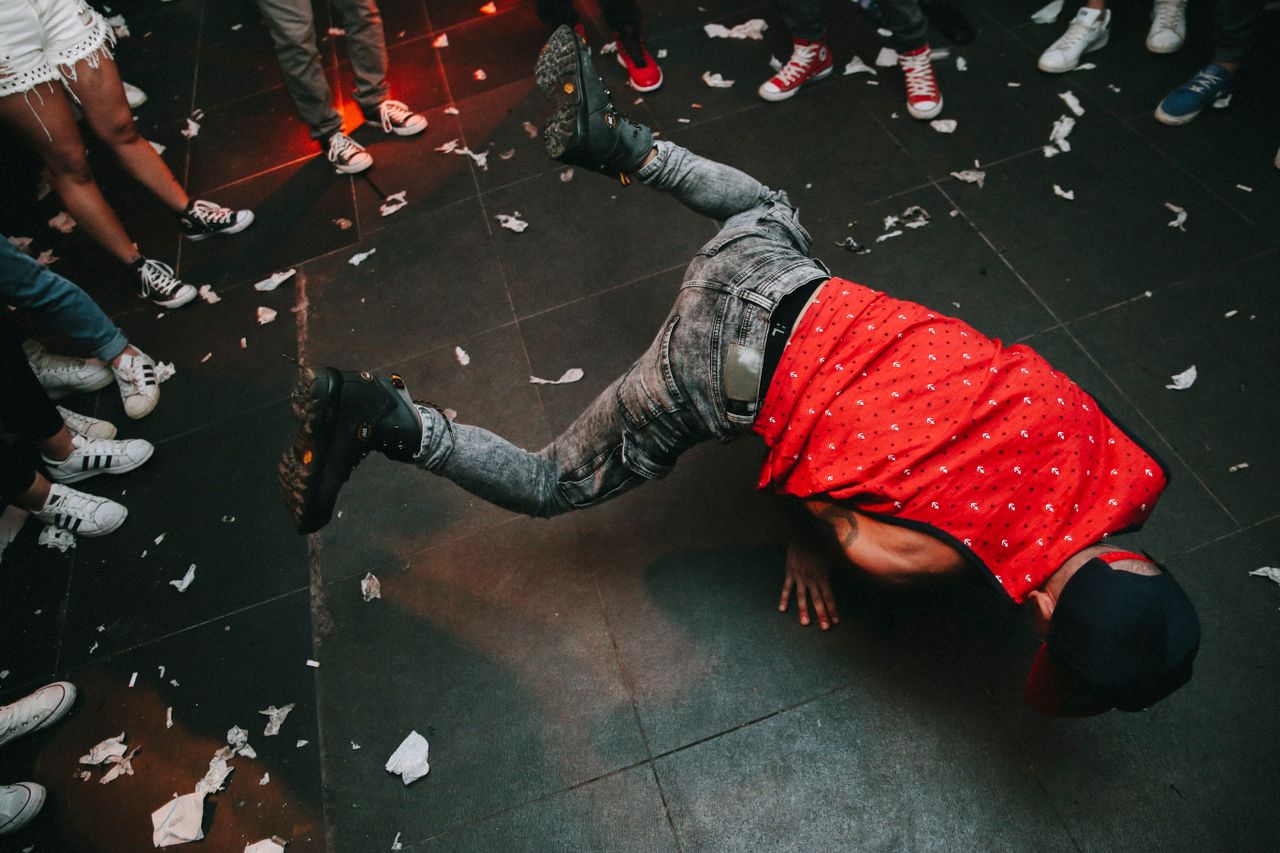 High-energy breakdancer performing on a crowded indoor floor during a lively event.