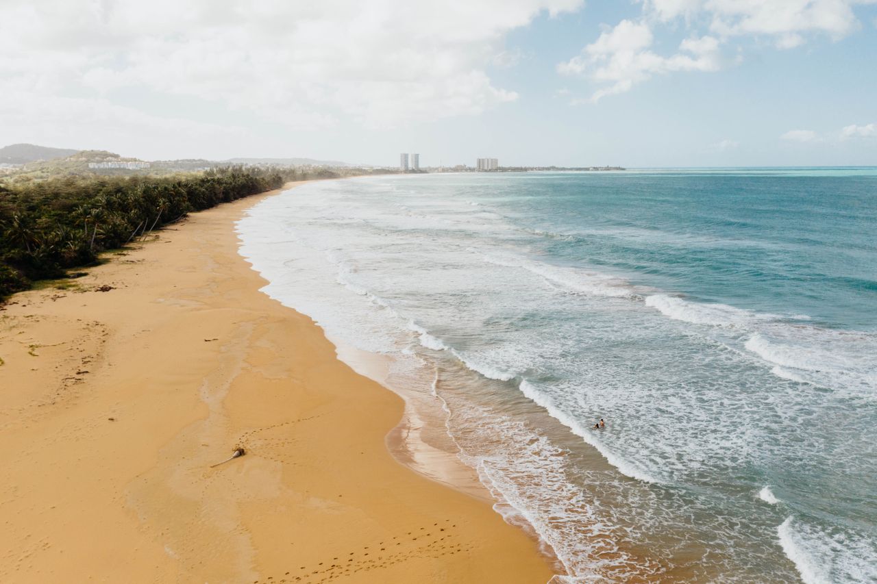 Golden sand beach in Puerto Rico with gentle waves, ideal for a tropical summer vacation.
