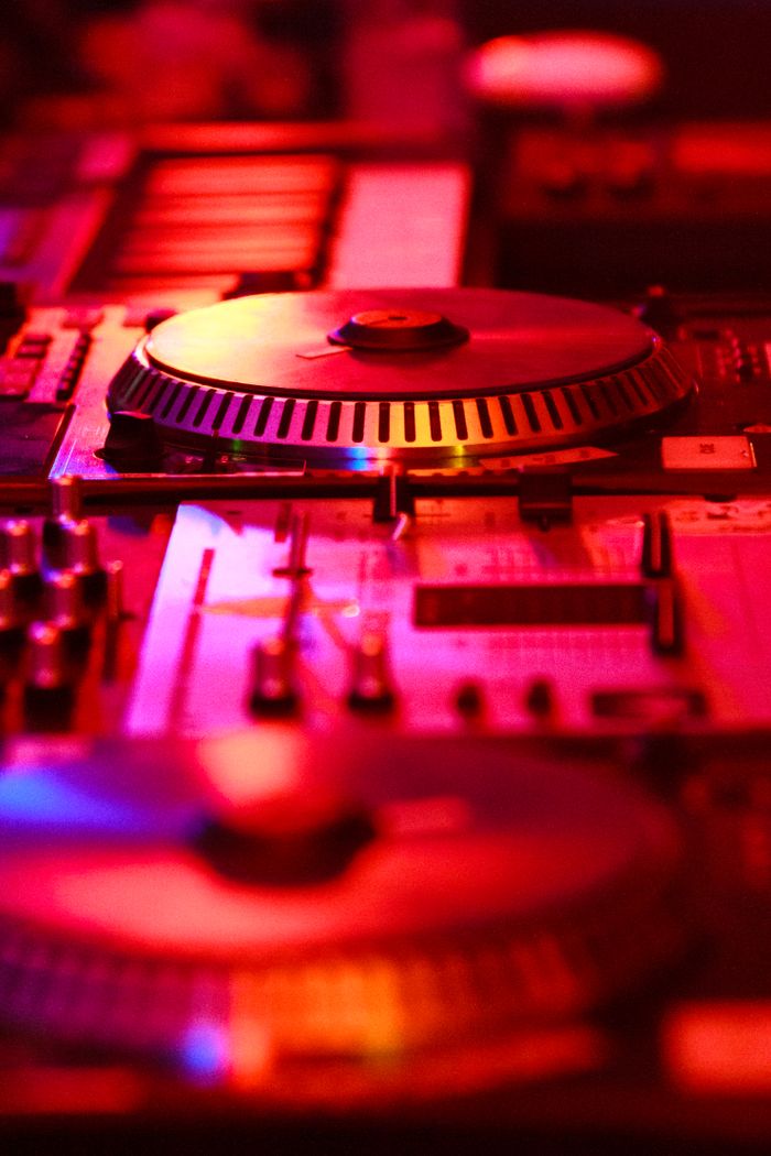 Close-up of a DJ turntable with colorful lighting in a music studio environment.